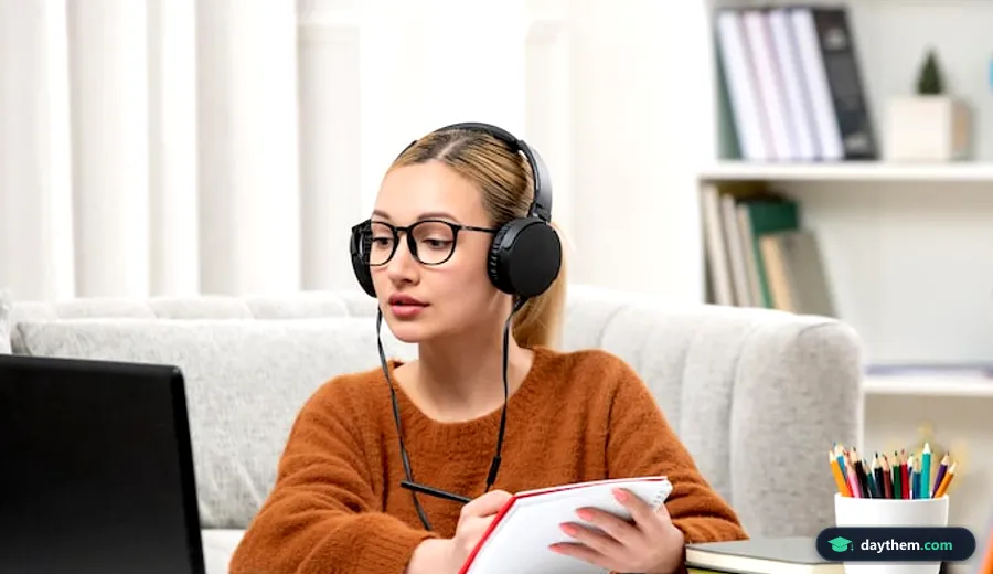 Học sinh đeo kính mặc áo len ngồi học trên máy tính và ghi chép vào vở