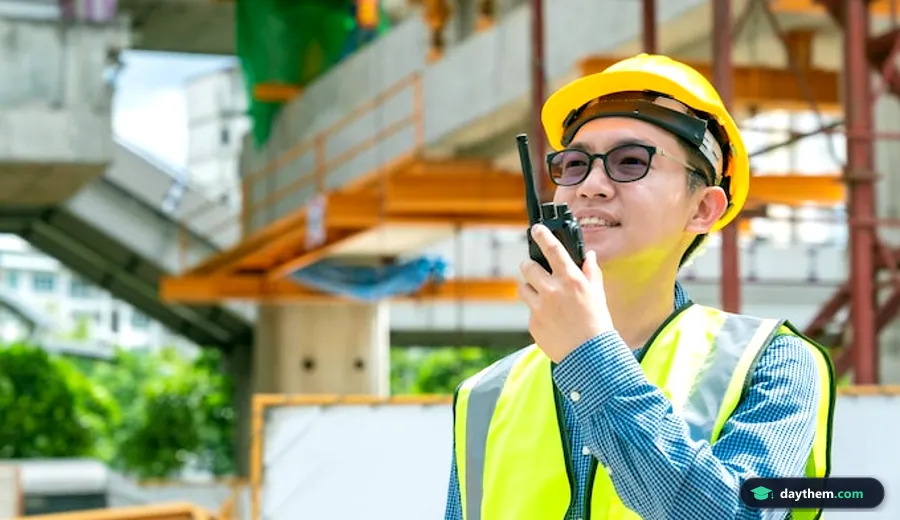 Kỹ sư nam người châu Á đội mũ bảo hộ và đeo kính đang sử dụng bộ đàm tại công trường xây dựng ở Hưng Yên